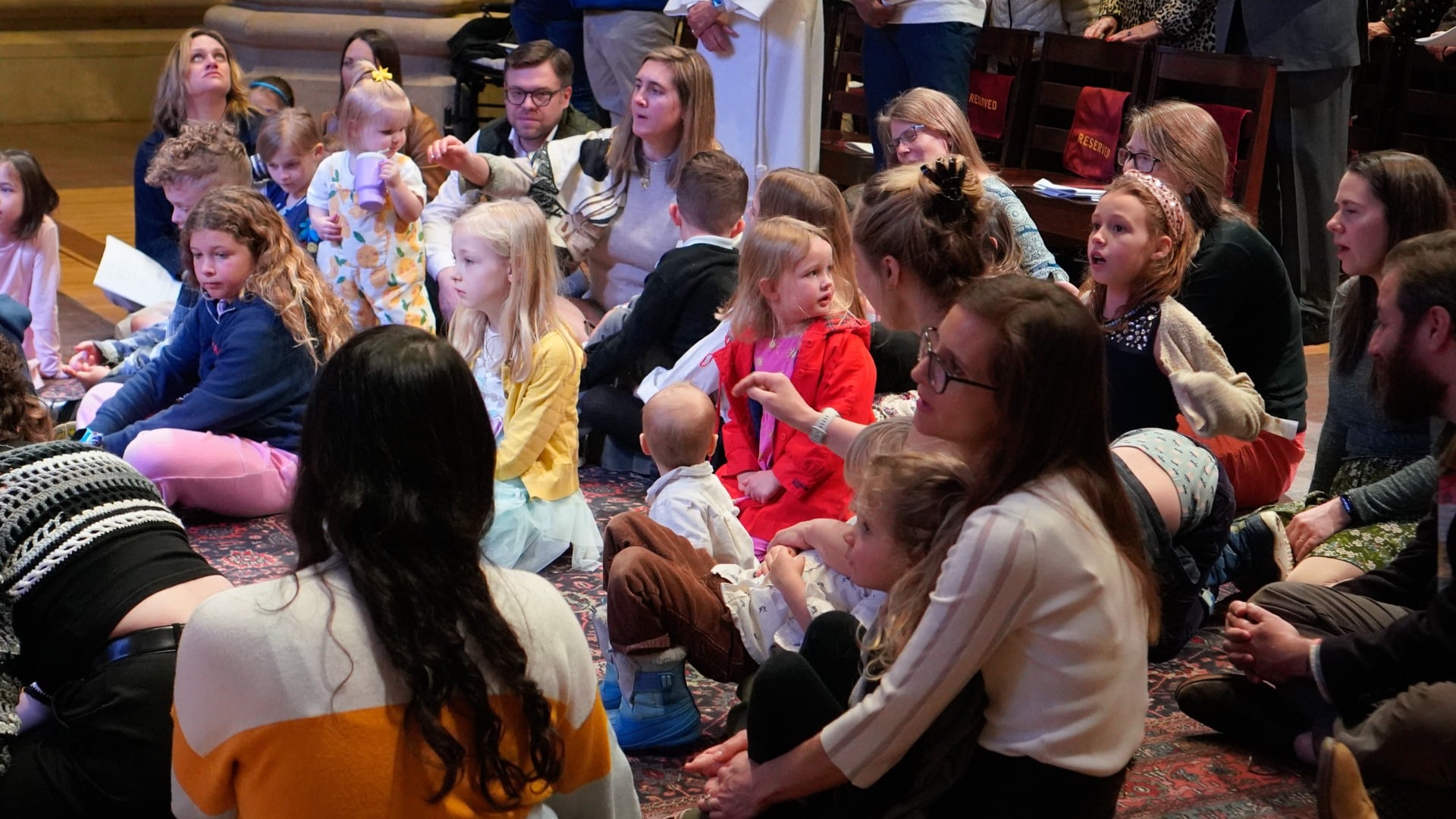Children and families gather together on the floor during a worship service at St. John’s Cathedral in Denver.