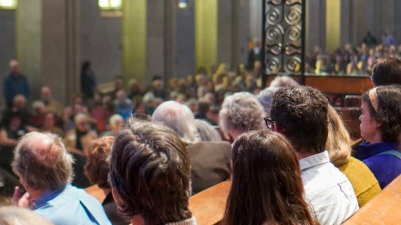 Congregants gathered for worship inside St. John’s Cathedral in Denver, surrounded by Gothic arches, stained glass and ornate ironwork.
