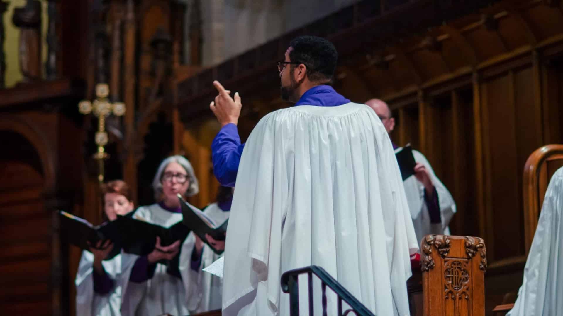 A choir director leads singers during a funeral or memorial service at St. John’s Cathedral in Denver.