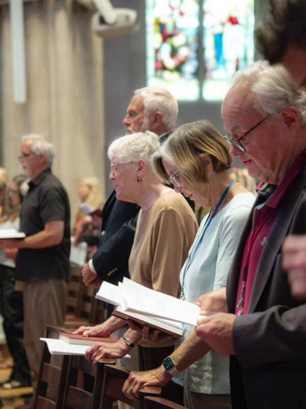 Members of St. John’s Cathedral in Denver standing together with prayer books during a worship service.