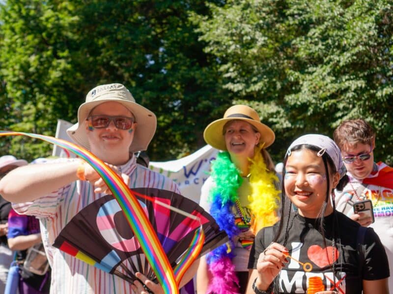 Members of the Saint John’s Cathedral community celebrate at Denver Pride with rainbow accessories, flags, and colorful Pride fans.