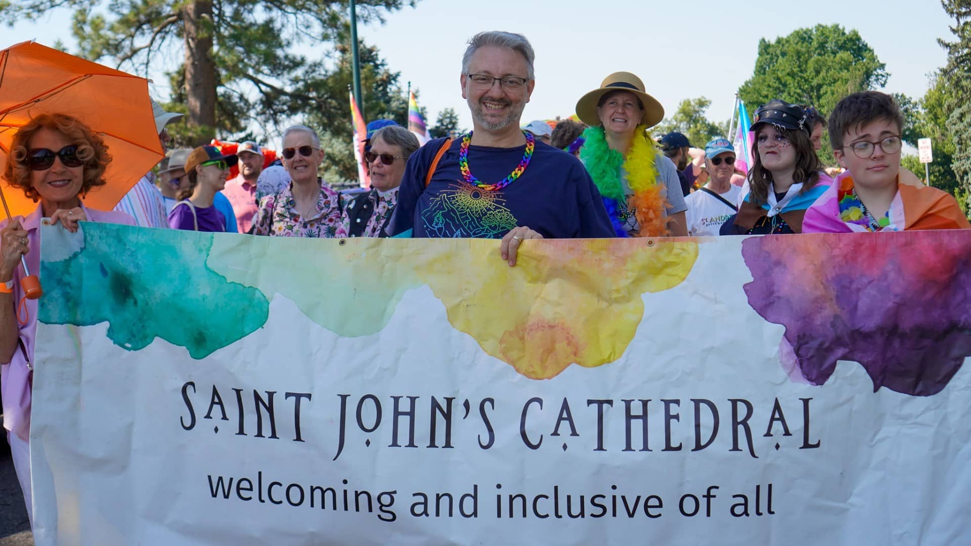 Members of Saint John’s Cathedral gather behind a “welcoming and inclusive of all” banner during Denver Pride.