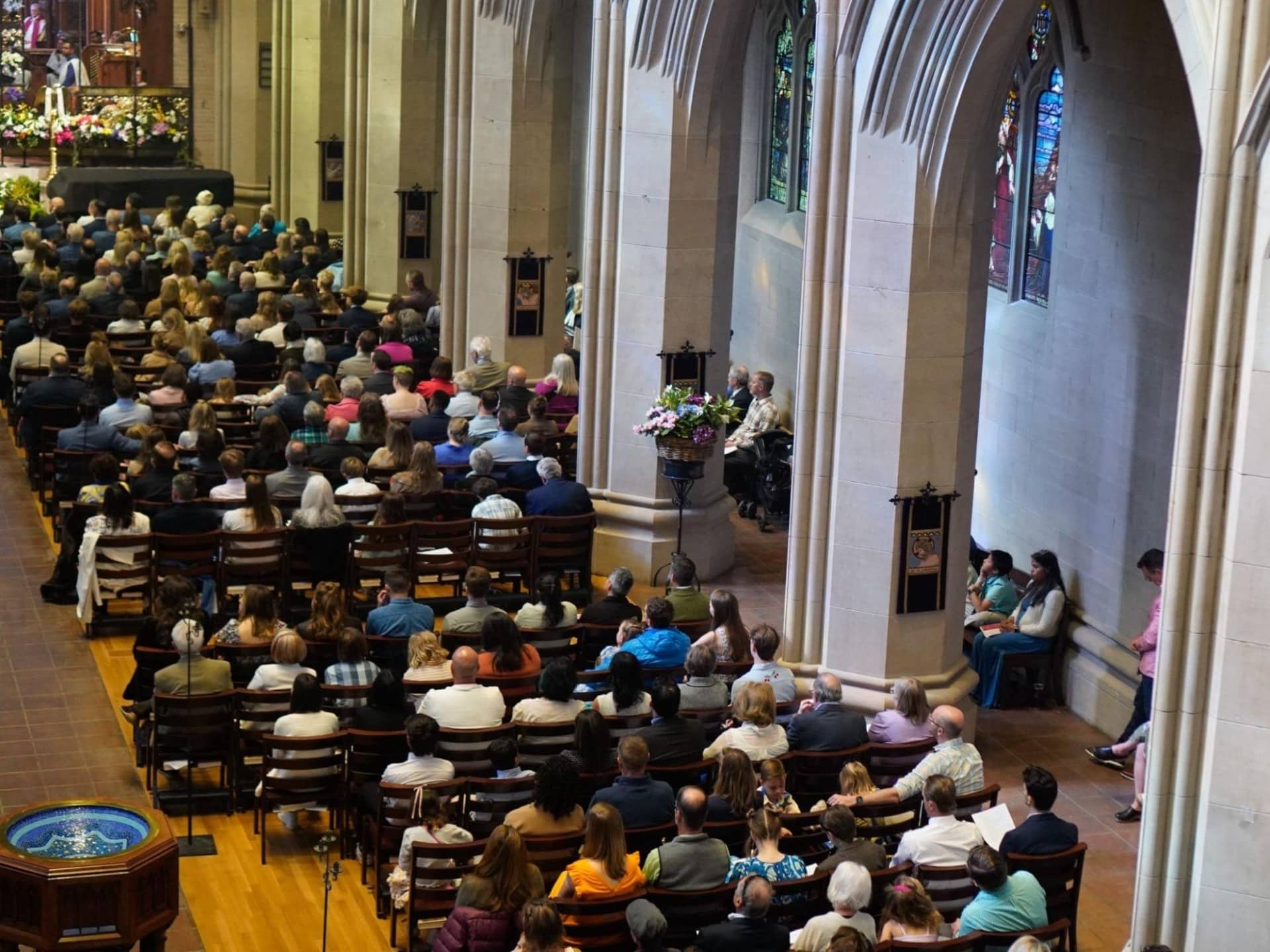 Congregation gathered for worship inside St. John’s Cathedral in Denver, surrounded by Gothic arches and stained glass windows.